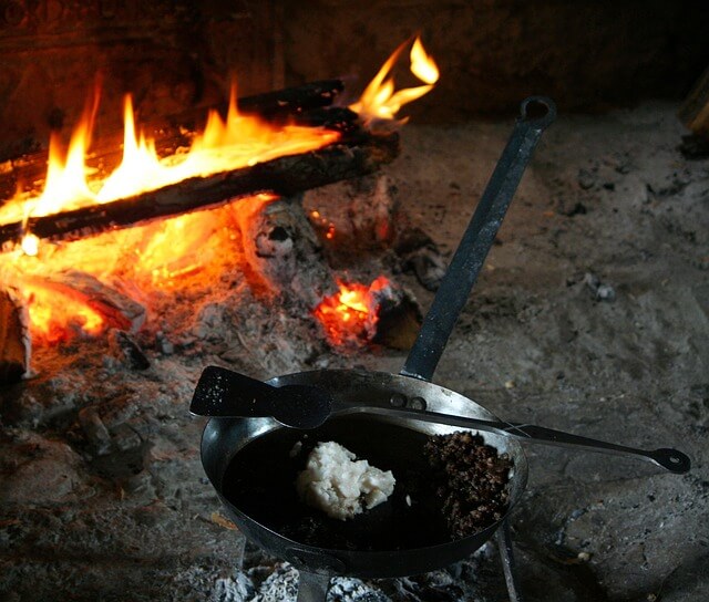 鉄フライパンを使って炭火でご飯を炒めている
